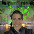 Geronimo smiling inside Bogart House with green lights and balloons behind him